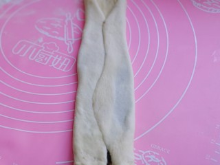 16、中种豆沙吐司面包,将擀好的长舌状两边向中间对折，用擀面杖轻轻擀长。