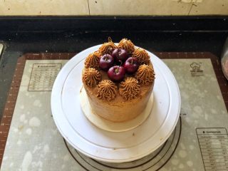 22、圣诞咖啡奶油蛋糕,22、将剩余的咖啡奶油霜装入裱花袋里，裱花袋里提前装入齿形裱花嘴，在蛋糕表面挤上花型，中间放入车厘子装饰一下即可。