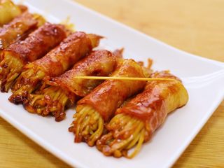14、金针菇培根卷,用筷子夹出来装盘,并除去牙签。培根卷已经成型,很容易就可以去除牙签。