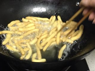 12、蔓越梅沙琪玛,锅内倒入花生油，煤气灶用小火加热，八分热时放入面条，用筷子翻拌，煎至金黄色捞出。