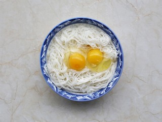 2、面条鸡蛋饼,剩面条放入大碗中，打入两个鸡蛋。