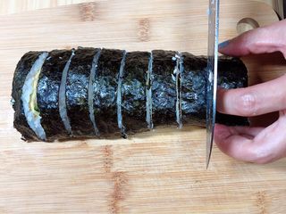 16、金枪鱼胚芽米寿司 | 便当,用刀将寿司卷切成均匀的小段儿。