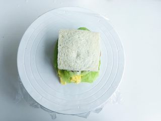 8、爱的沼夫三明治,最后鸡蛋啊 鸡蛋丝 千岛酱 色拉酱一轱辘的依次码好 盖上吐司片 裹紧保鲜膜 然后对半切开就好了 （做这种厚款三明治最好铺上一层保鲜膜 看见我铺的保鲜膜没有 仔细瞅瞅 这样紧紧的裹住再切一是不易散 二是方便又好看 当然不介意你用更加高端大气上档次的油纸之类的啦）