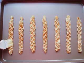 13、豆沙麻花棒,依次做好放入烤盘中。鸡蛋一个打散，用小刷子刷上一层全蛋液（分量外）