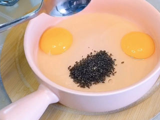 2、芝士火腿三明治,碗里敲两个鸡蛋，加入一勺黑芝麻，黑芝麻提升香味又增加营养