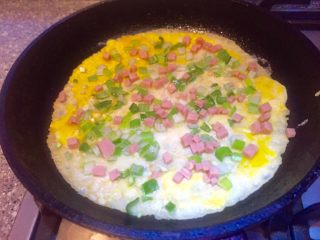 14、辣椒香葱午餐肉鸡蛋卷饼,马上撒入葱花,辣椒丁,午餐肉粒。