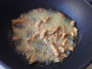 9、糖醋里脊,开大火，把油温烧至200度左右，下入里脊肉二次复炸，炸至上色酥脆捞出