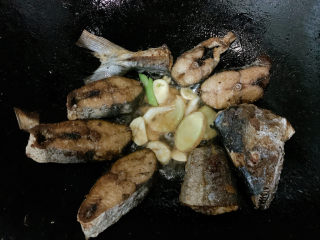 6、红烧鲅鱼,将锅中煎好的鱼肉移开留出一定空隙，加入姜蒜片、葱白爆香。