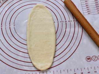 13、椰蓉奶香面包圈,慢慢用擀面杖擀成稍长些的椭圆形。