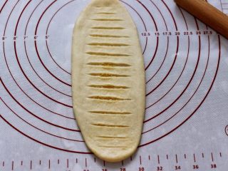 14、椰蓉奶香面包圈,用锋利的刀片在面团表面均匀的割几刀，注意只切透上面一层即可。（擀的时候用力要均匀，否则容易将椰蓉馅挤出）