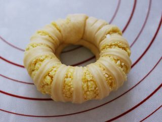 16、椰蓉奶香面包圈,拿起两头往中间合拢，把其中一头卷紧些，插入另一头捏紧捏实。