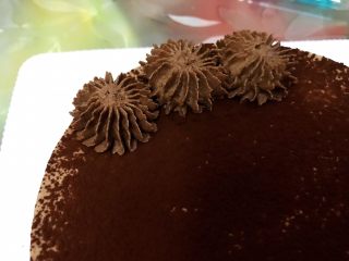 18、醇厚浓郁的巧克力慕斯蛋糕,取出冷藏好的巧克力奶油加入糖粉打发至硬挺，装入裱花袋里挤出小花