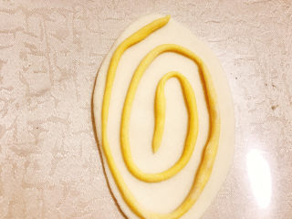 11、贝壳馒头（南瓜）,取少许南瓜面团搓成细长条，盘在白色面皮上