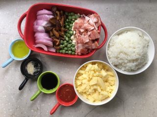 1、芝士培根焗饭,准备好所有原材，洋葱切丝，香菇泡软切片，培根切块，芝士碎、油、蕃茄酱、胡椒粉、生抽、青豌豆、玉米粒和米饭等备好。