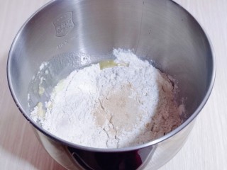 3、花式椰蓉面包,加入高筋面粉，最后加入酵母粉，再用旁边的面粉盖上酵母粉！启动厨师机1档揉面10分钟！