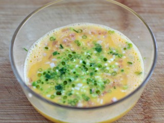 4、芝士培根鸡蛋卷,将培根和小葱放入鸡蛋中