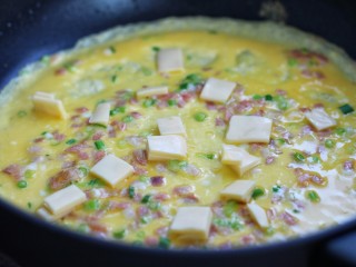 7、芝士培根鸡蛋卷,晃动锅子将蛋液摊成蛋皮，定型后撒适量芝士