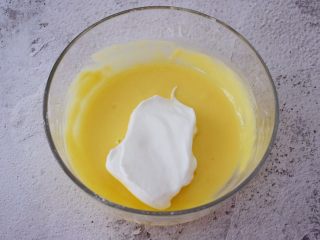 9、舒芙蕾松饼,把三分之一的蛋白霜放入蛋黄中翻拌均匀