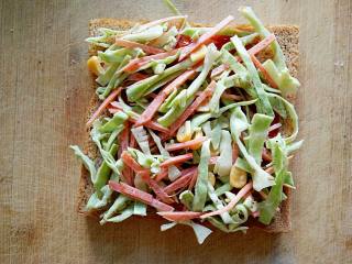 7、沼夫三明治,在涂抹好番茄酱的吐司片上均匀铺上一层卷心菜沙拉。