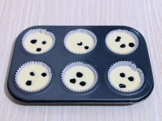 10、新手入门级～蓝莓椰蓉马芬蛋糕,再把做好的蛋糕液倒入纸托中，每个纸托里再放上几颗蓝莓，轻轻震动模具，将气泡震出。