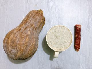 1、南瓜焖饭,主要食材如图所示示意，南瓜一小段、半截腊肠、大米。