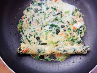 15、#咸味#菠菜海苔玉子烧,再次摊入蛋液，等到蛋液快要凝固时放入刚刚卷好的蛋卷一起卷起来