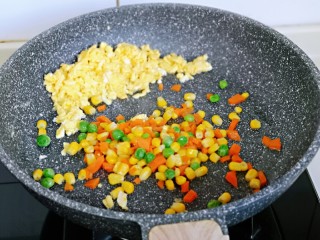 9、小熊便当套餐,把鸡蛋碎放在锅旁边，加入焯水的彩蔬翻炒均匀。