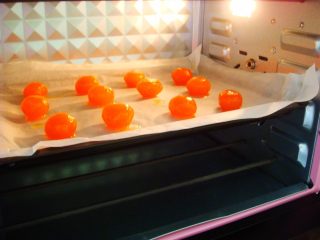 2、广式莲蓉蛋黄月饼,烤盘里铺上油纸，摆放上蛋黄。