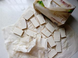 3、菌茹烩豆腐,放在不掉屑的纸巾上,吸净水分,这样在煎的时候油不会溅出来,也能缩短煎的时间。