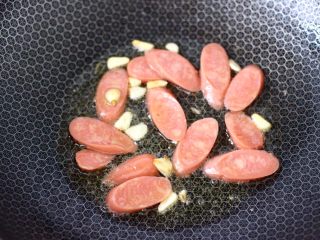 6、火腿肠时蔬炒意面便当,另起锅倒入橄榄油烧热，先爆香蒜片，再放入火腿肠翻炒均匀。