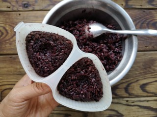 3、紫米饭团,晾凉的熟紫米饭压入饭团模具（使劲押紧，防止散开）。