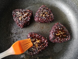 7、紫米饭团,撒适量的白芝麻，再刷一层料汁，料汁可以多刷几遍，让料汁渗进饭团更入味。