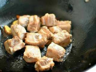 2、排骨焖饭,锅里放入少量橄榄油，放入姜片八角爆香后加入焯水后的排骨，放冰糖炒至表面微微发黄。