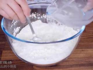 1、春日田园披萨,把面粉倒入碗里，倒入速溶酵母搅拌，海盐和水混合物边倒边搅拌