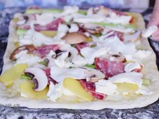 11、春日田园披萨,把芦笋间隔平铺在上面， 再依次放上土豆片、蘑菇、萨拉米香肠，最后铺上芝士，撒上黑胡椒