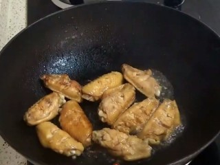 6、香煎鸡翅,锅烧热后，加入两勺花生油，放入腌制好的鸡翅，小火煎