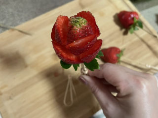 3、拨丝冰糖草莓,用小刀轻轻切成玫瑰花形，插上竹签