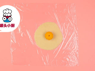 4、网红Q香橘子大福,保鲜膜上放适量白豆沙，擀平成圆形，放上橘子果肉，包起来，定型后撕掉保鲜膜