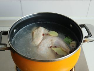 3、葱油白斩鸡,汤锅内加适量水，能淹没鸡就好，放入几片姜和一些葱段，几个花椒粒以及少许食盐。
