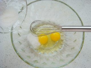 2、蔓越莓鲷鱼烧,盆中打入两个鸡蛋，加入白砂糖。