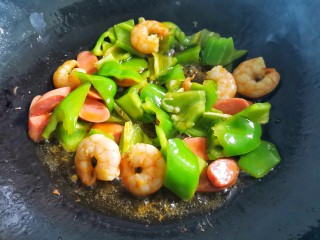 6、黑椒虾仁炒乌冬面,加入切好的火腿,青椒炒熟,