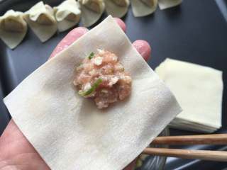 4、红油抄手,开始包抄手，取一张馄饨皮，将肉馅放在一个角上