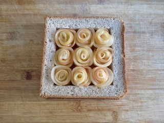 15、苹果玫瑰花土司,直到做完九朵苹果玫瑰花，全部置于土司框中。