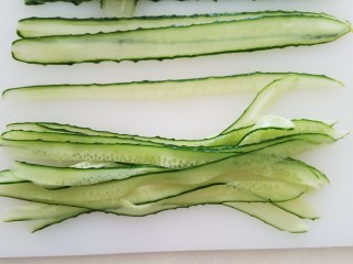 4、菠萝蛋包饭,黄瓜用刮皮器竖着刮成长条状，然后也切成食指宽的条。