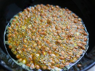 5、油炸花生米,开小火慢慢炸，锅中开始冒泡后开始翻炒，炸至花生皮即将爆开就关火。