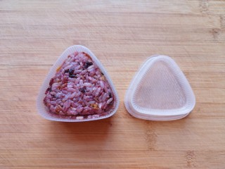 10、紫米饭团,拌好的米饭放进饭团模具里面，盖上饭团模具的盖子压实（如果没有模具，直接用保鲜膜包起来捏成团也可以）。