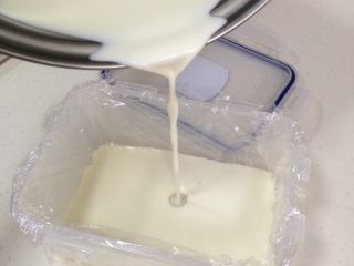 5、椰奶小方,放凉后，倒入垫有保鲜膜的保鲜盒内，盖好盖子，入冰箱冷藏3小时。