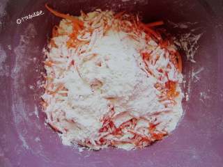 4、粉蒸胡萝卜丝,挤掉水分的胡萝卜。撒一些干面粉，要均匀的搅拌至每根胡萝卜都沾上干面粉。