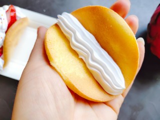 14、草莓抱抱卷,取一个蛋糕片放在手心，挤上奶油。乳脂奶比较好打发，打发到尖峰状态，装一个裱花嘴即可。