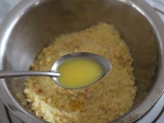 3、海底世界果冻,捣碎的消化饼干放入盆中，加两勺融化的黄油拌匀！（两勺黄油只是一个大概的量，黄油加到饼干碎中拌匀以后，用勺子压一下饼干，能成团，不会太黏就可以）